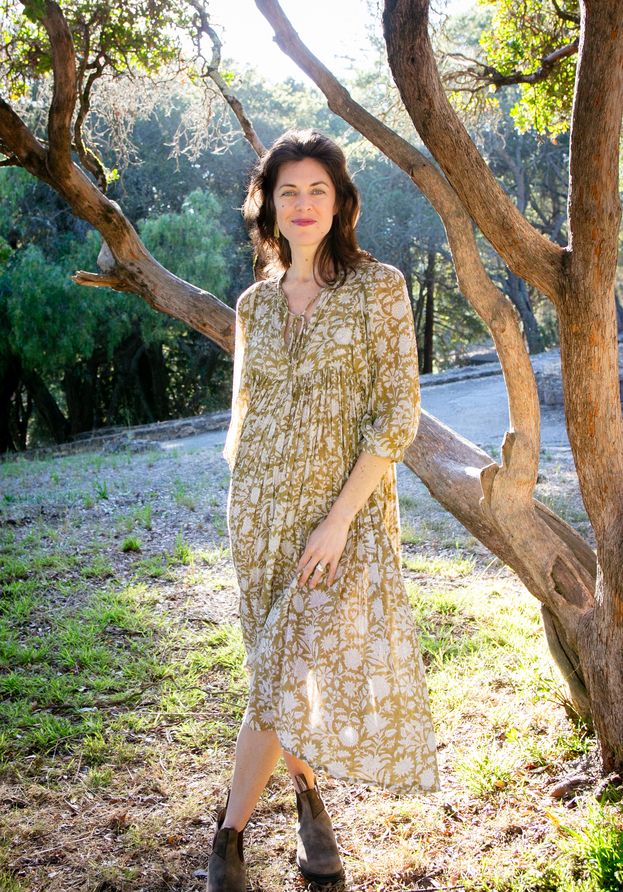 Katie Schmidt, MA, somatic therapist in Oakland, California, standing beside an oak in bright natural light