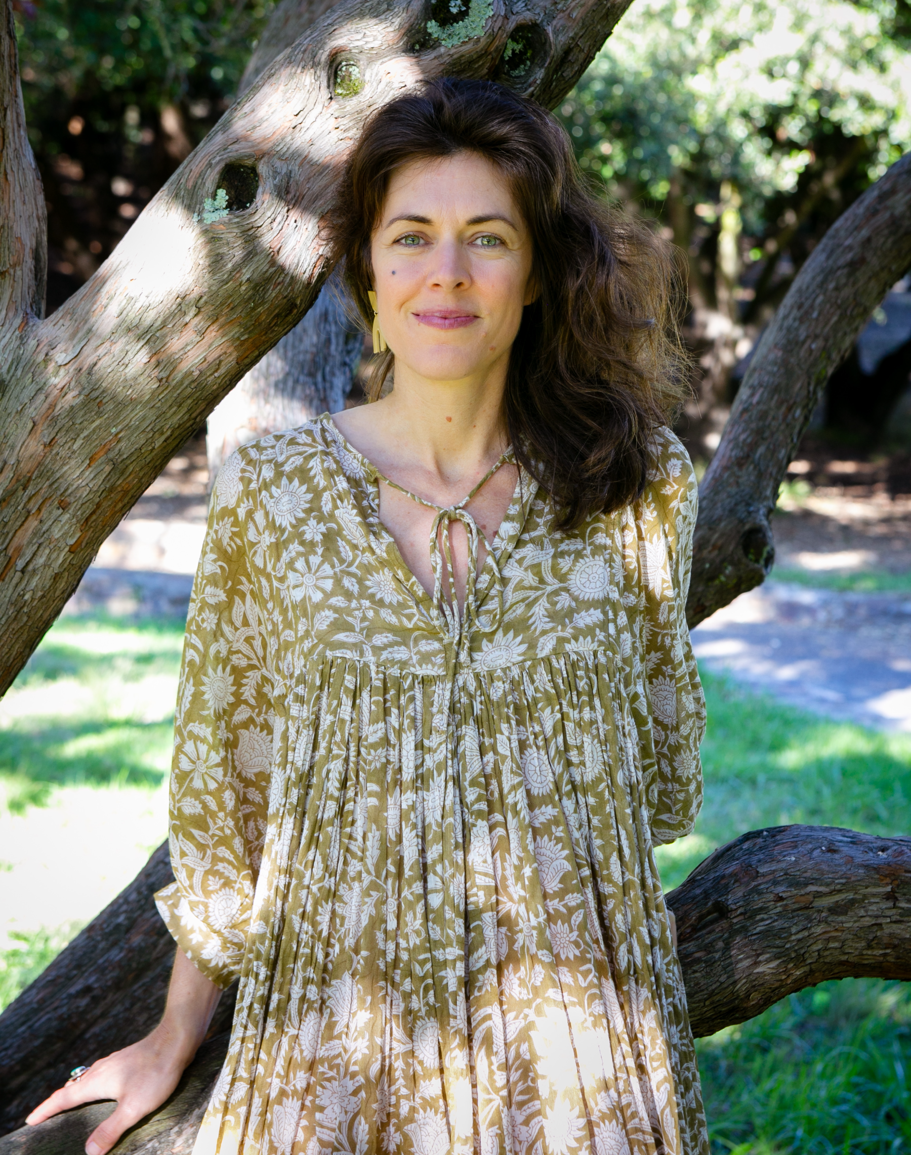 Katie Schmidt, somatic therapist in Oakland, California, standing among the branches of an old oak tree